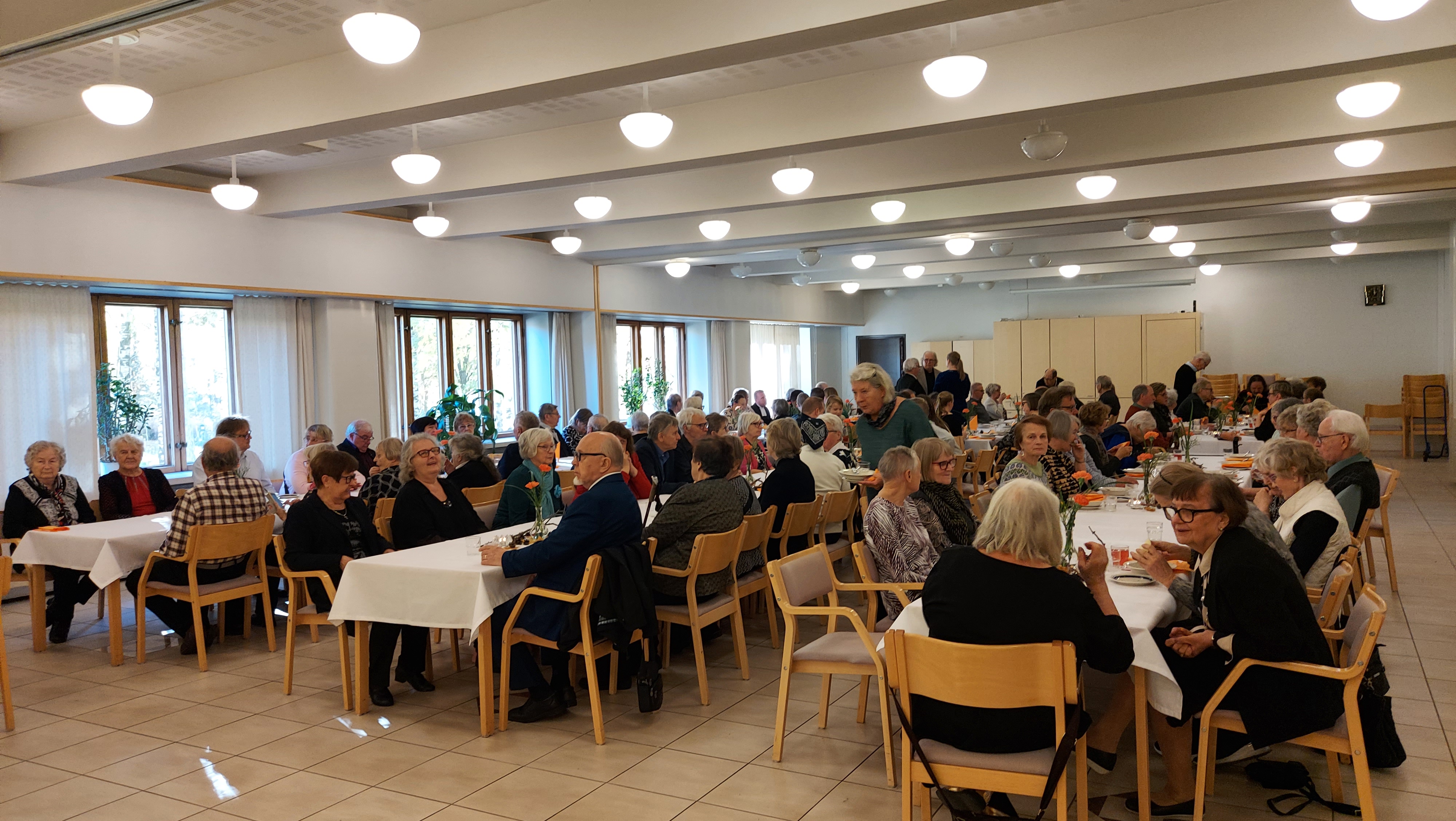 Ihmisiä kahvipöydissä.