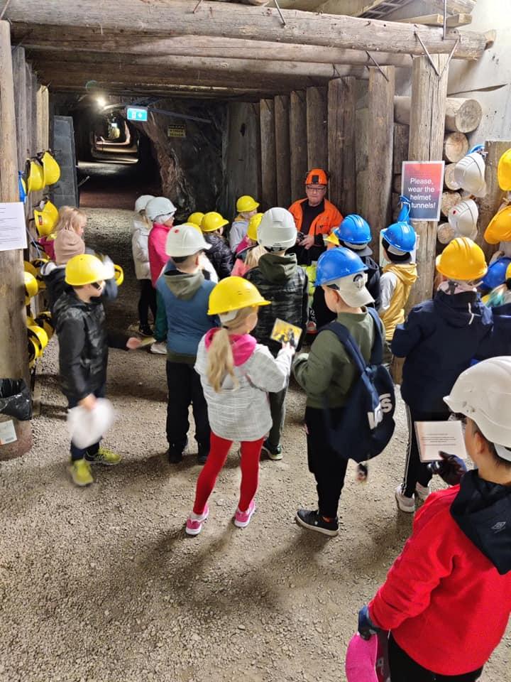 Lapsia keltaisissa kypäröissä kaivostunnelissa.