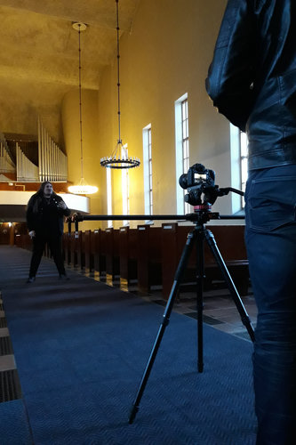 Musiikkivideon kuvausta varten Antti Railio seisoo kirkon keskikäytävällä.
