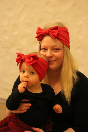 Äidillä ja tyttärellä on päässään samanlaiset punaiset rusettipannat.