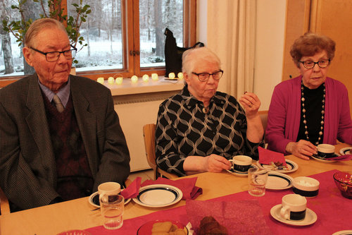 Kerholaiset vakavina kahvipöydässä.