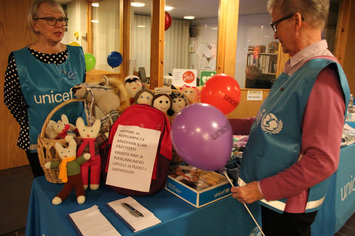 Unicefin vaaleansinisiin liiveihin pukeutuneet naiset myyntipöytänsä ääressä.