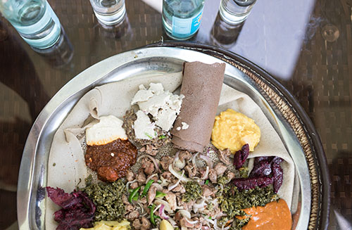 Afrikkalainen ateria erilaisin kastikkein ja muhennoksin paistetun ohukaisen päällä.