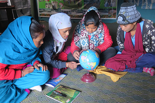 Nepalilaiset tytöt tutkimassa karttapalloa.
